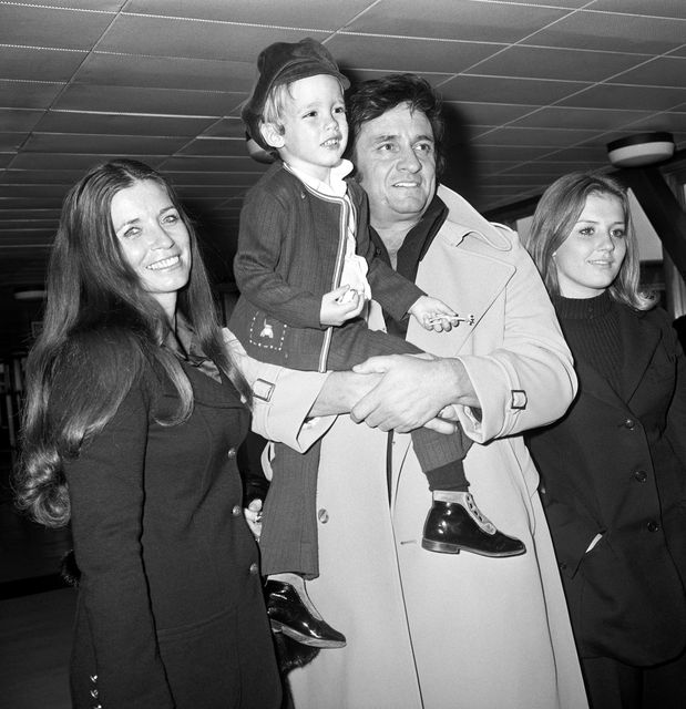 Singer Johnny Cash at London Airport carrying his son, John, with his wife, June Carter (left) and stepdaughter, Rosie (PA)