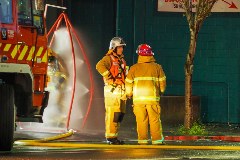 Firefighters stand outside the hostel in Wellington, where at least six people were killed after a fire broke out. Photo: AP