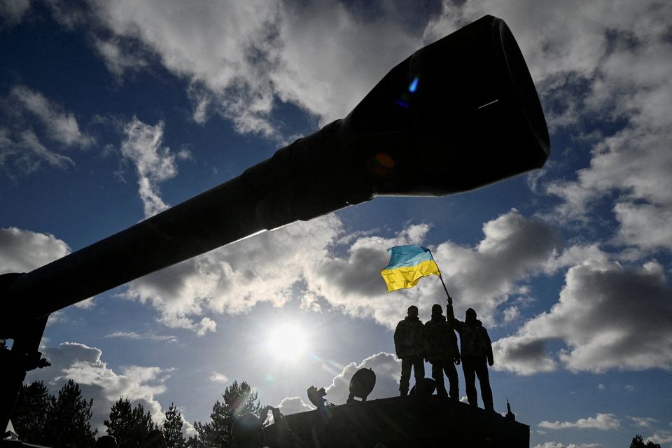 Ukrainian personnel hold a Ukrainian flag as they stand on a Challenger 2 tank during a training exercise at Bovington Camp, near Wool in southwestern Britain, February 22, 2023. REUTERS/Toby Melville/File photo