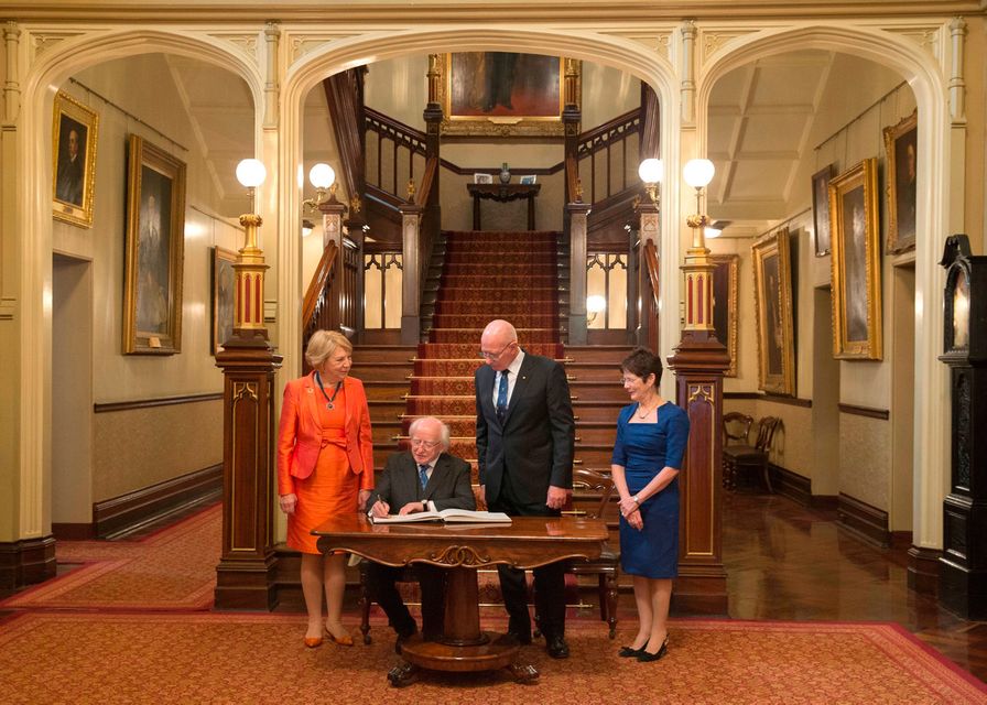 Ireland's President Michael Higgins, second left, and his wife Sabina, left, sign a visitor's book with New South Wales state Governor David Hurley, second right, and his wife Linda, right, looking on at Government House in Sydney, Australia, Tuesday, Oct. 17, 2017. (AP Photo/Steve Christo, Pool)