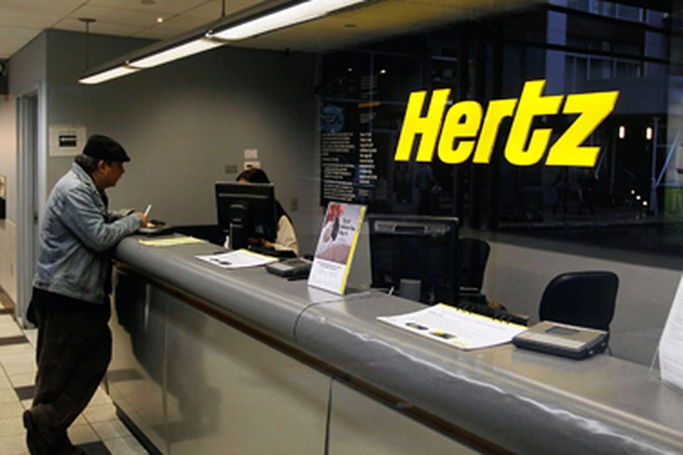 A man talks to a staff member at a Hertz counter. Photo: Getty Images