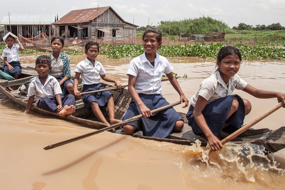 A group of children come back from school riding their boat