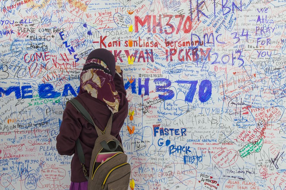 An unidentified girl writes messages for MH370 in Kuala Lumpur.