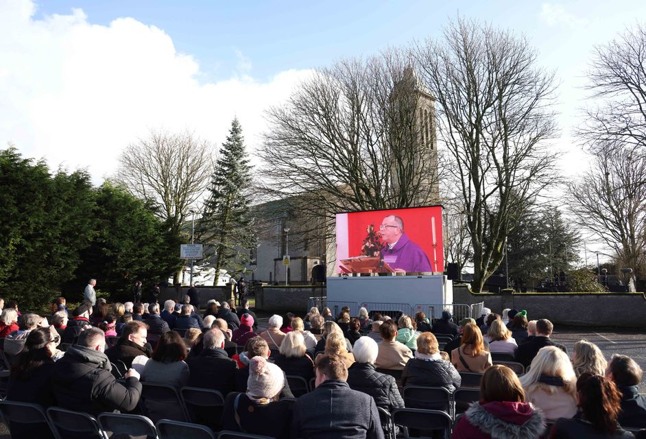 Members of the public seated outside to watch a video feed of the state funeral of former taoiseach John Bruton at St Peter and Paul’s Church, Dunboyne, Co Meath. Photo: Julien Behal/Government Information Service