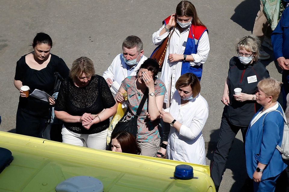 Medics and friends help a woman board an ambulance at a school after a shooting in Kazan, Russia, on May 11. Photo: AP/Roman Kruchinin