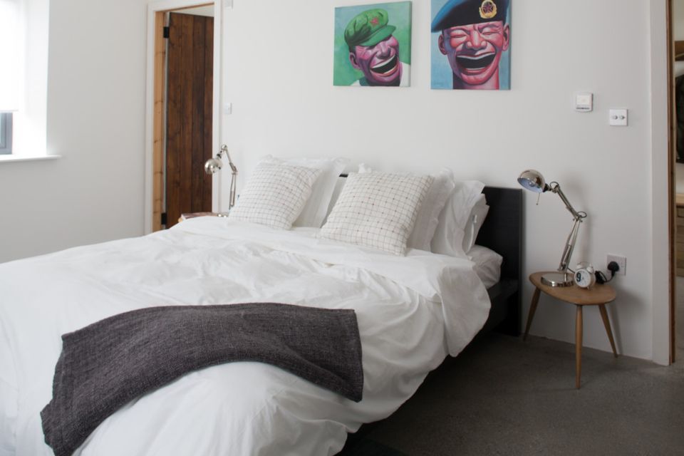 The bedrooms are simply furnished in white and grey. The pictures over the bed are copies of the work of a Chinese dissident artist.