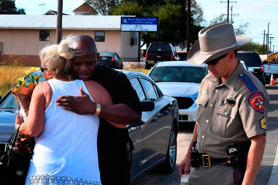 Local resident Jamie Rose is hugged by church member Raymond Antonio as she delivers flowers to the First Baptist Church in Sutherland Springs, Texas. Photo: AFP/Getty Images