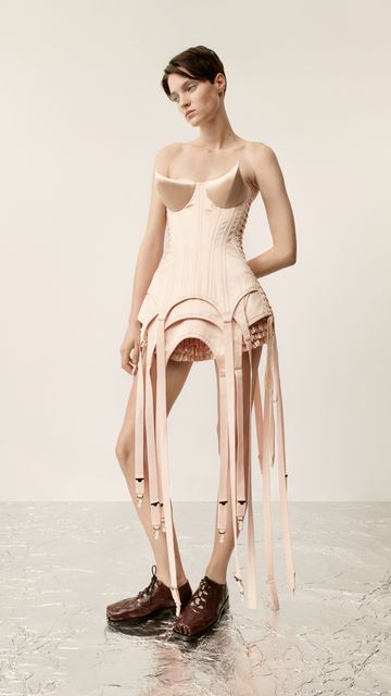 Layered corset dress in rose poudre silk duchesse satin with suspenders, “thorn” conical breasts and satin duchesse shorts with all-over folded bias ruffles worn with ghillie brogues, Jean Paul Gaultier x Simone Rocha