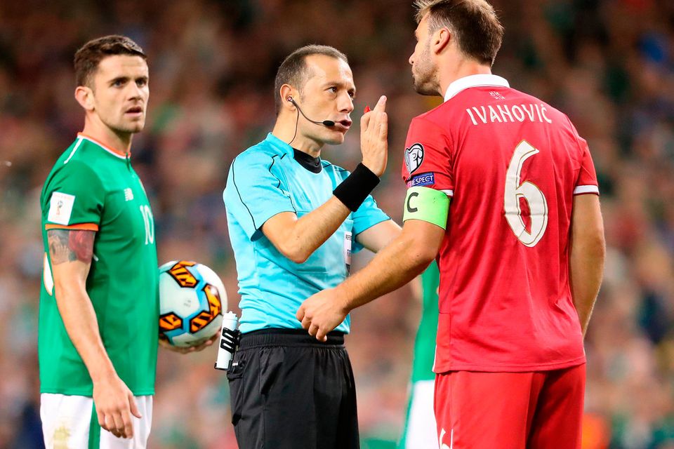 Referee Cuneyt Cakir speaks to Serbia's Branislav Ivanovic against Ireland
