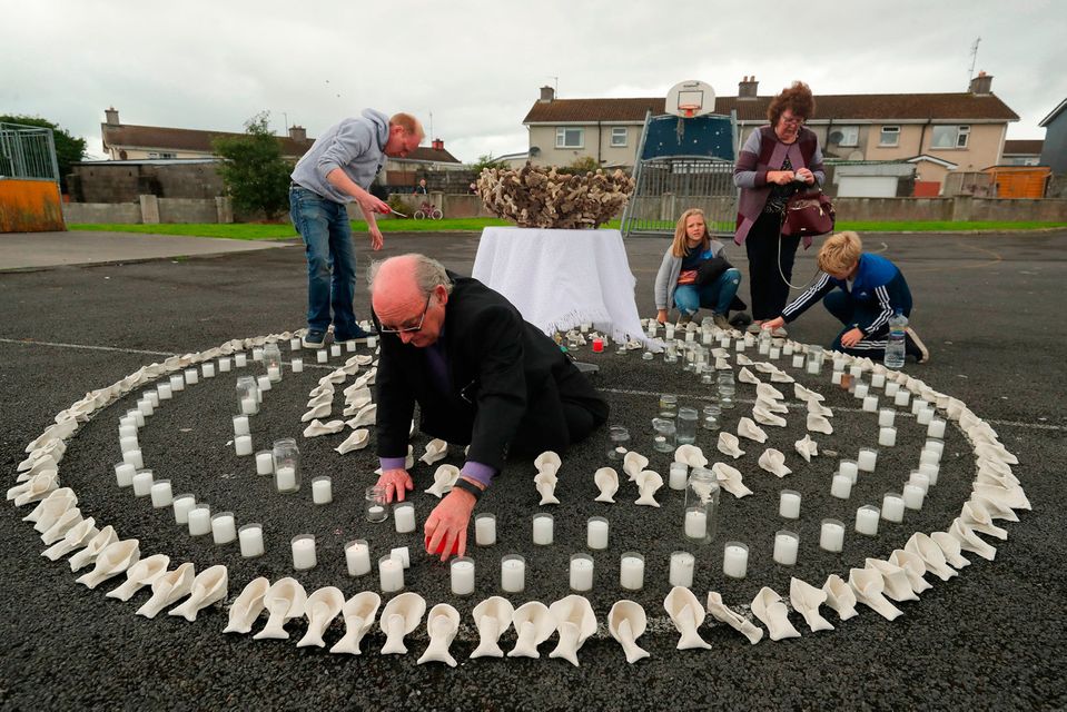 Aiden Corless lights candles in an artwork of clay children’s shoes at the site of the former Tuam home for unmarried mothers in Co Galway yesterday. Photo: Niall Carson/PA