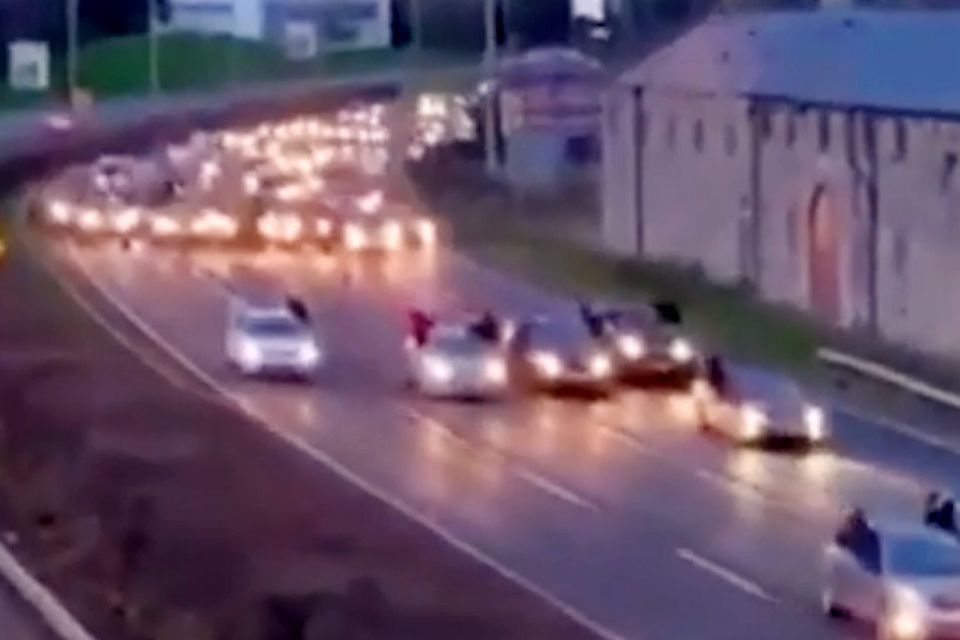 The video shows a convoy of cars, with passengers hanging out the windows, ahead of two sulky racers leading another trail of cars on the busy N7