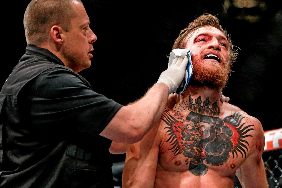 Conor McGregor is treated for a cut over the right eye at the end of the first round