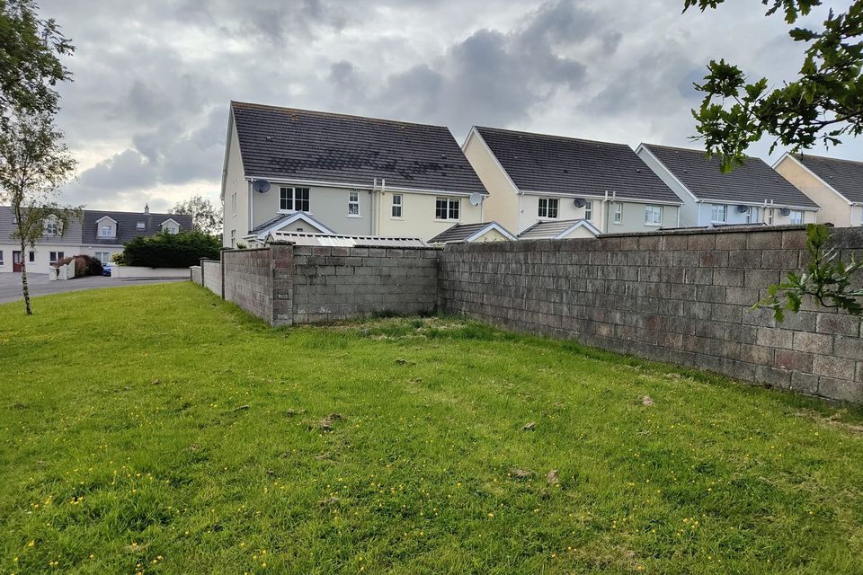 The boundary wall divides back gardens and a public green area.