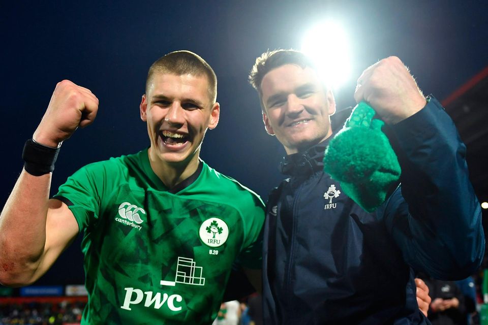Sam Prendergast celebrates with assistant coach Mark Sexton after completing an U-20s Grand Slam with victory over England at Musgrave Park last night. Photo: David Fitzgerald/Sportsfile