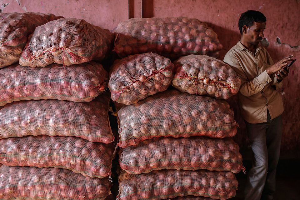 Many-layered problem: A worker next to sacks of onions at a wholesale market in Mumbai. Photo: Bloomberg