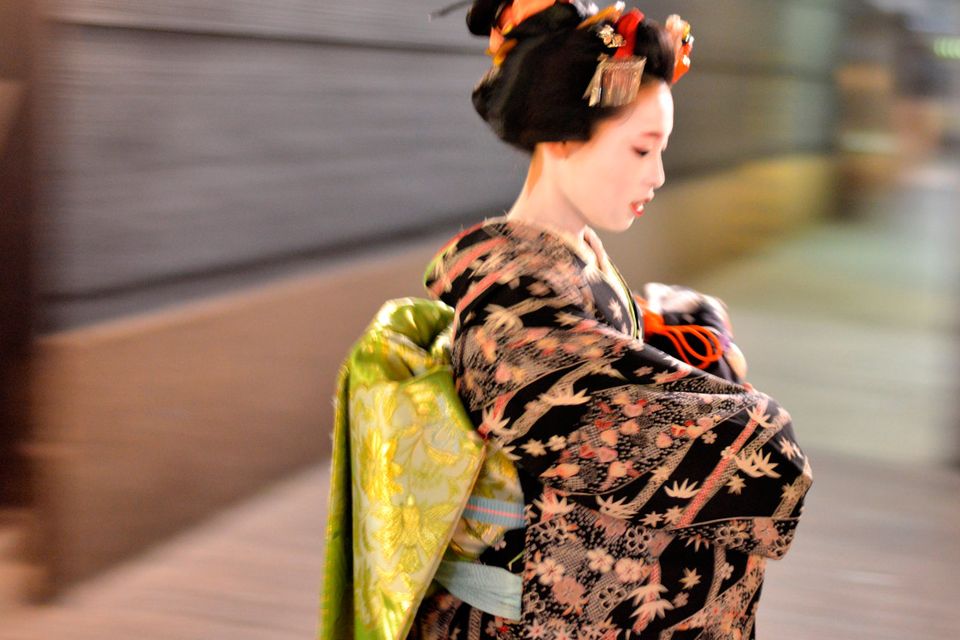 A maiko, or apprentice geisha, walks between teahouses in Gion, Kyoto