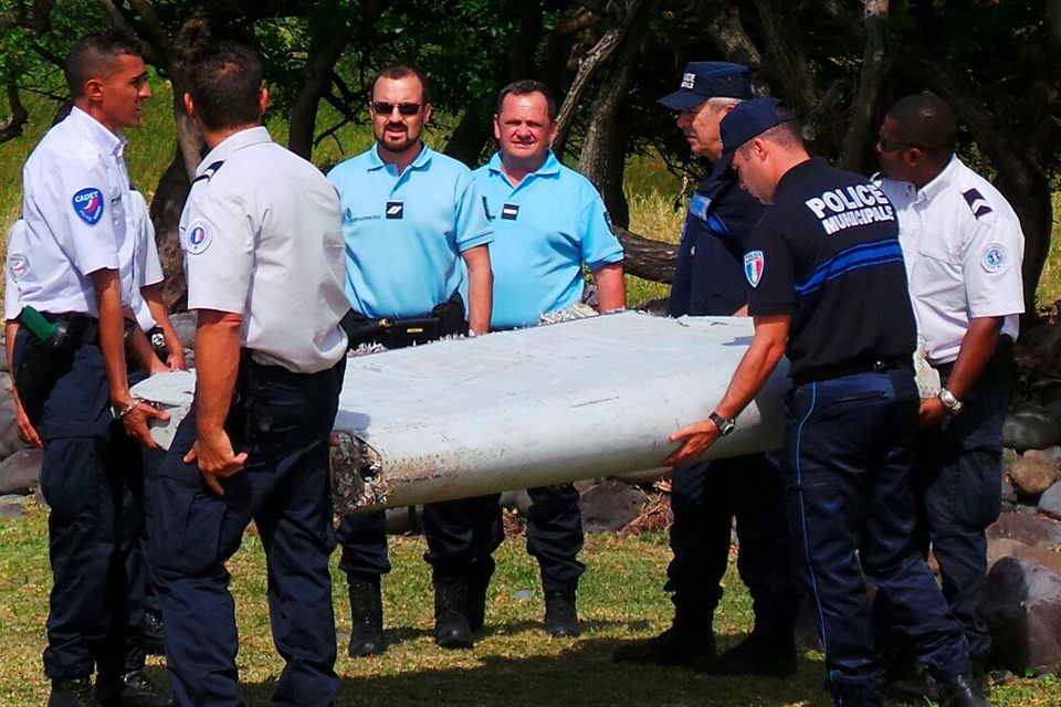 French gendarmes and police carry a large piece of plane debris which was found on the beach in Saint-Andre, on the French Indian Ocean island of La Reunion, July 29, 2015. France's BEA air crash investigation agency said it was examining the debris,  in coordination with Malaysian and Australian authorities, to determine whether it came from Malaysia Airlines Flight MH370, which vanished last year in one of the biggest mysteries in aviation history. Picture taken July 29, 2015.     REUTERS/Zinfos974/Prisca Bigot