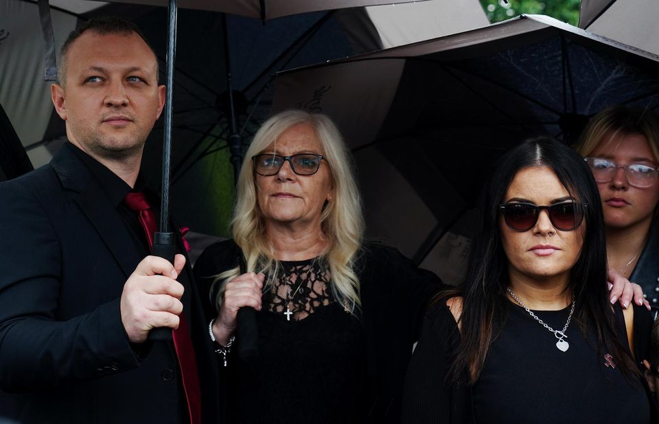 Christy Dignam’s wife Kathryn (second left) and daughter Kiera (second right) join people on Farnham Drive, Finglas (Brian Lawless/PA)