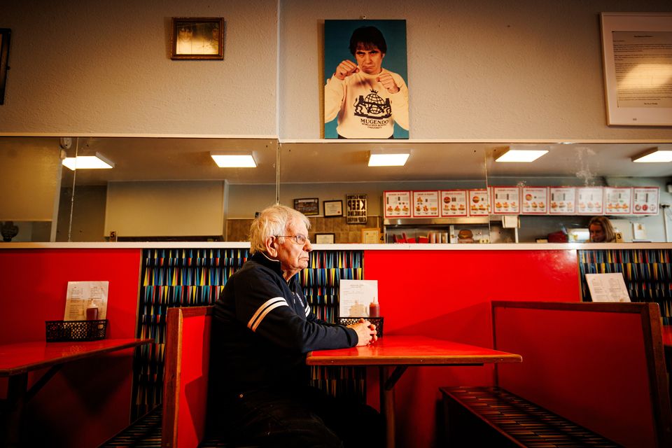 Fillipo Fusco sits under a photo of his younger years at the family takeaway on Meath Street. Pic: Mark Condren