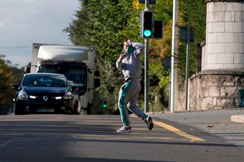 Ross Hutch tries to hide his face as he runs into the road to avoid photographers while leaving Dublin District Court. Photo: Collins Courts