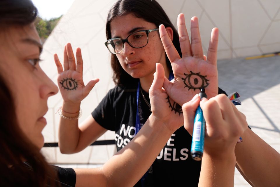 German climate activists draw eyes on their hands to signify they are watching delegates negotiating the phase-out of fossil fuels at Cop28 in Dubai. Photo: Getty