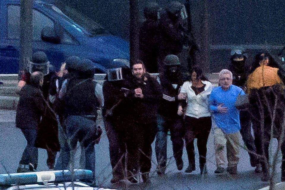 Security officers escort released hostages after they stormed a kosher market to end a hostage situation, Paris, Friday, Jan. 9, 2015