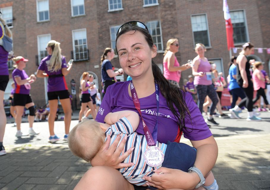 Mum Sarah Lester feeds her baby at the finish line after completing the race