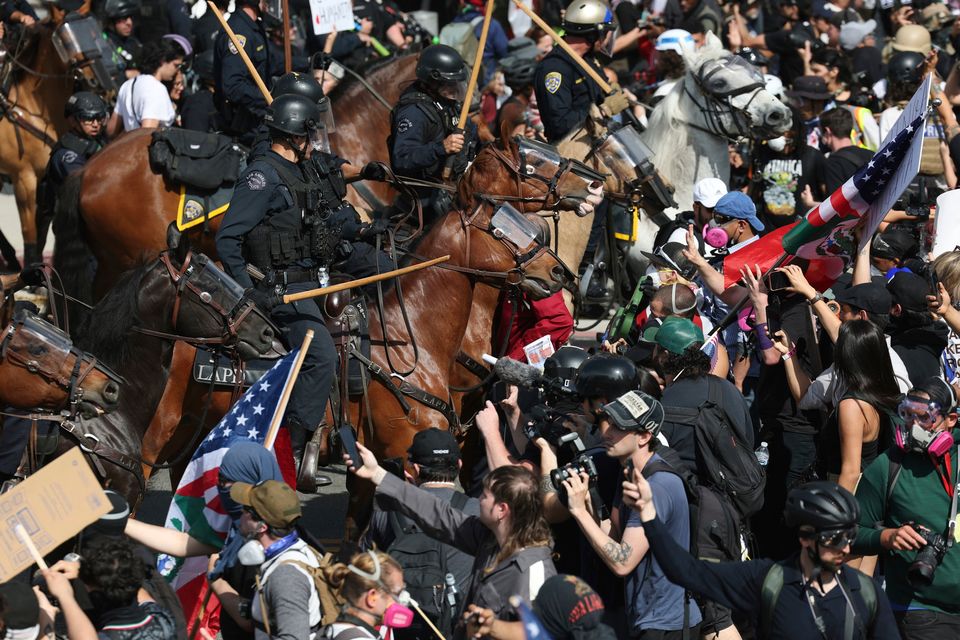 Stand-off: Protesters and police on horseback come face to face in LA last week. Photo: Ethan Swope/AP