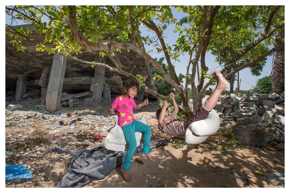 Children play on a makeshift swing in the shadow of their two-storey home which was destoryed by Israeli tanks in 2014. Photo: Mark Condren