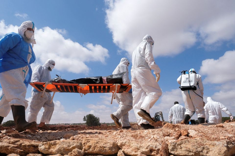 Volunteers carry a dead body before burying them at a mass grave, in the aftermath of the floods in Derna, Libya September 19, 2023. REUTERS/Esam Omran Al-Fetori