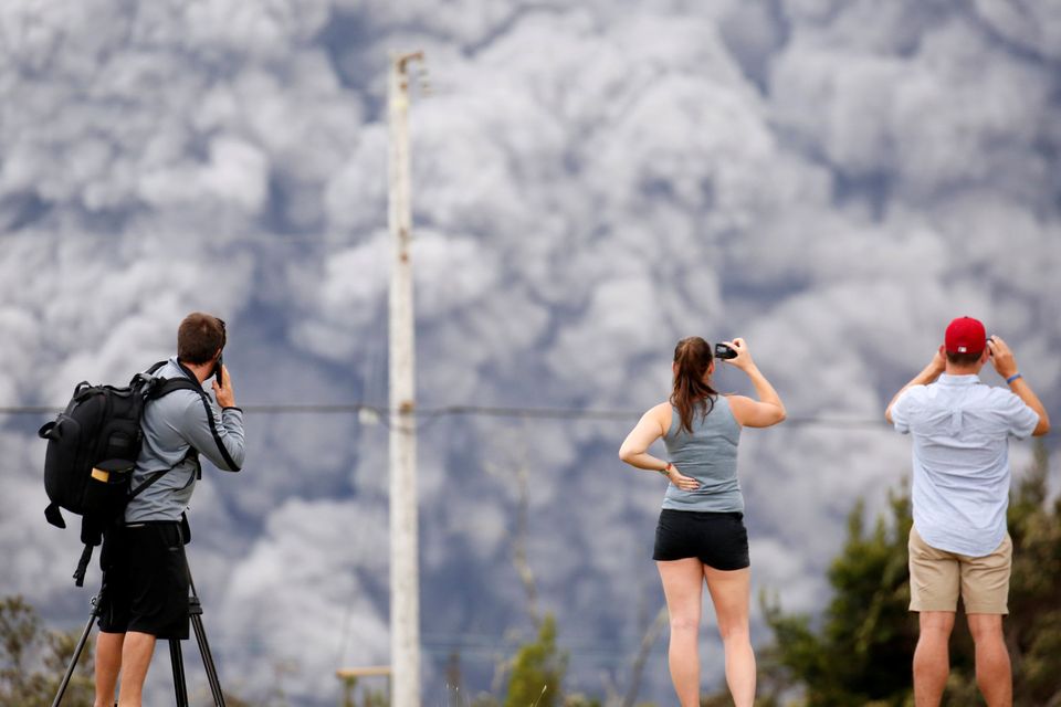 People watch as ash erupt from the Halemaumau crater near the community of Volcano during ongoing eruptions of the Kilauea Volcano in Hawaii, U.S., May 15, 2018.  REUTERS/Terray Sylvester
