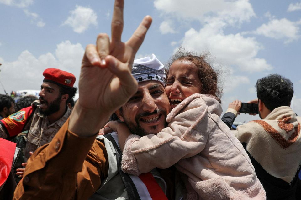 A freed prisoner gestures while holding a child after arriving at Sanaa Airport in Yemen on a Red Cross-chartered plane, after a prisoner swap. Photo: Reuters/Khaled Abdullah