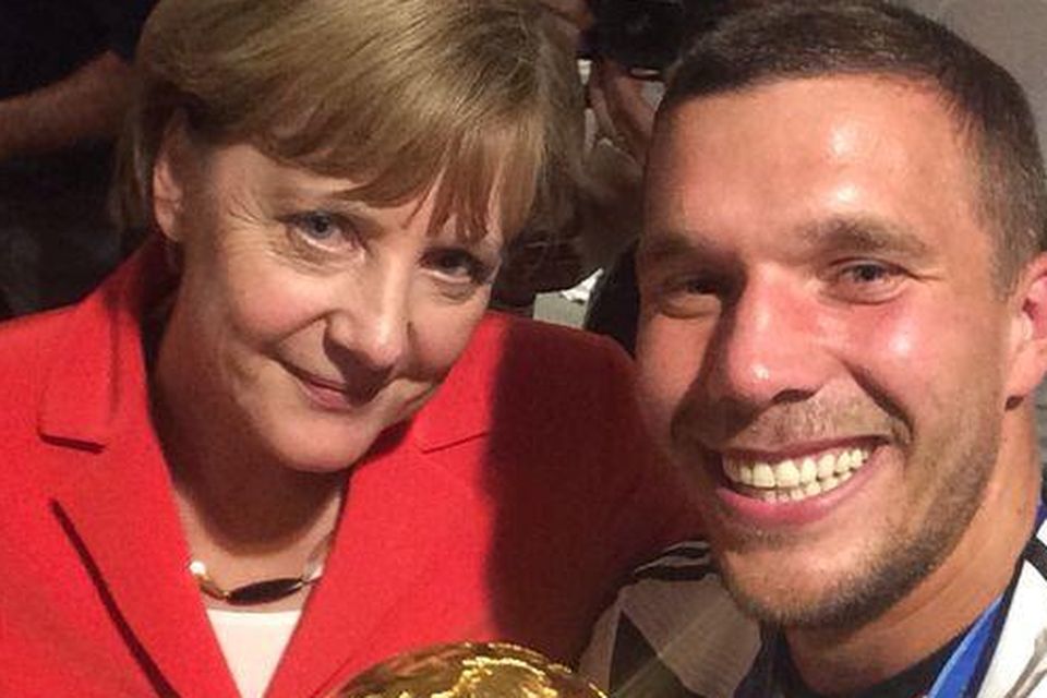 Lukas Podolski and Angela Merkel pose with the World Cup trophy