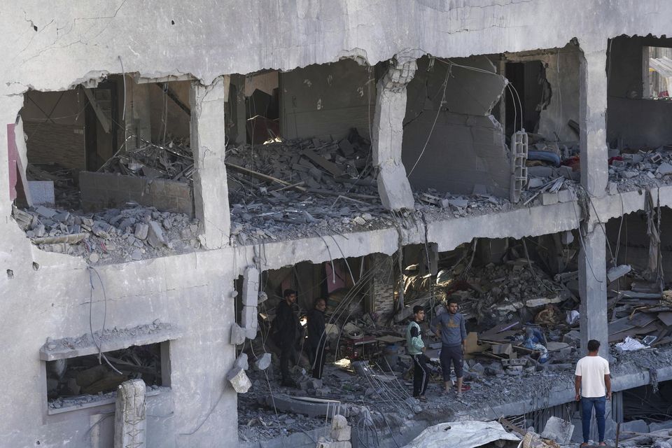 Palestinians inspect the rubble of a destroyed building in the Israeli bombardment of the Gaza Strip in Nusseirat refugee camp (Adel Hana/AP)