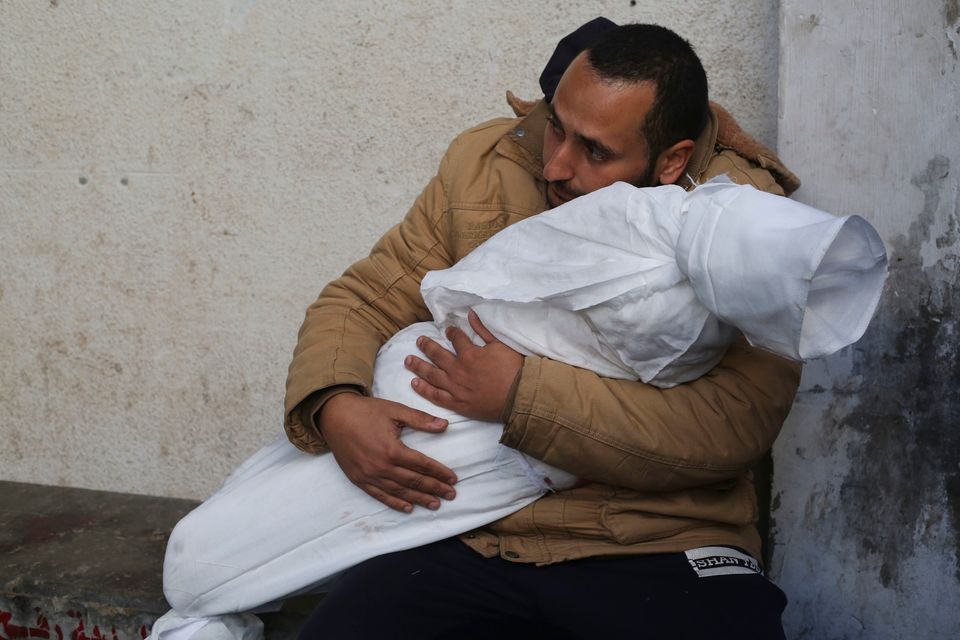 A Palestinian man holds his child, killed in the Israeli bombardment of the Gaza Strip, at a morgue in Rafah, Palestine, yesterday. Photo: AP