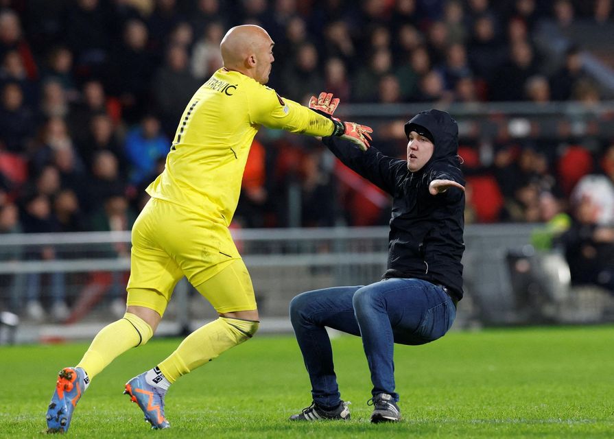A pitch invader clashes with Sevilla's Marko Dmitrovic. Photo: Reuters