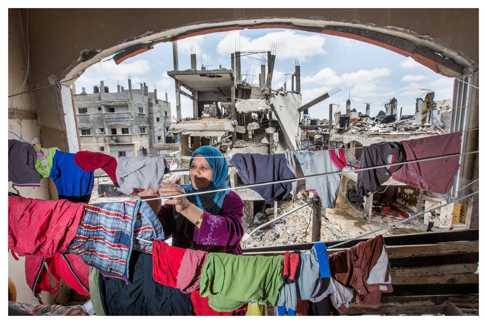 A woman hanging clothes inside her bombed out home in Gaza City. Photo: Mark Condren