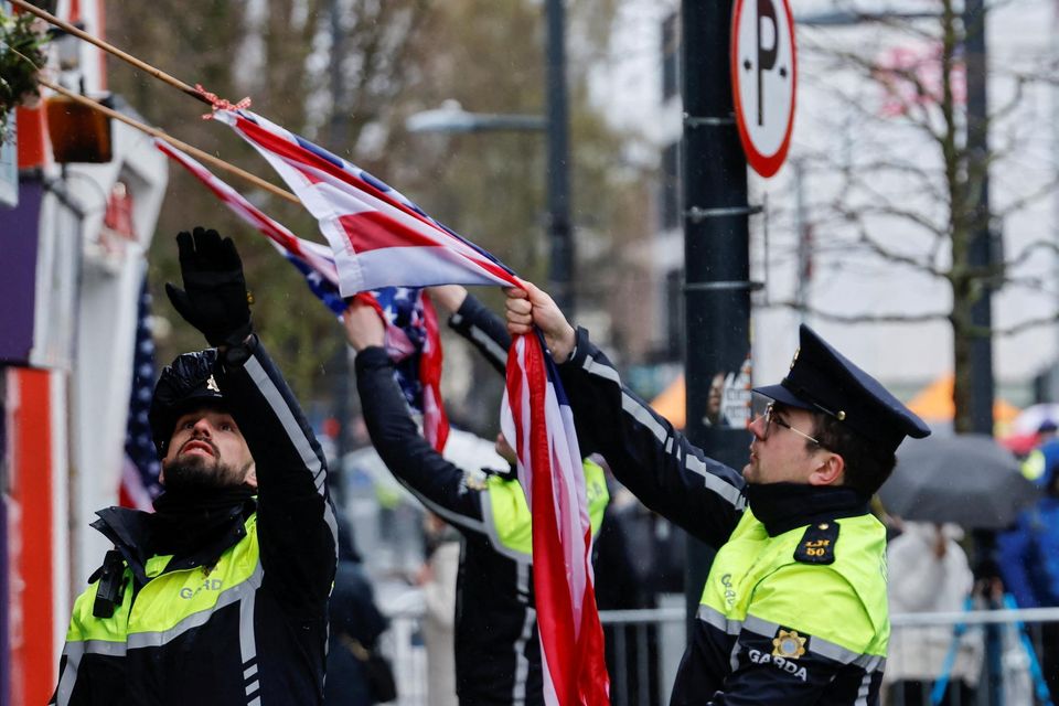 Police officers take down soaked flags due to the rain as U.S. President Joe Biden visits Dundalk, Ireland, April 12, 2023. REUTERS/Clodagh Kilcoyne