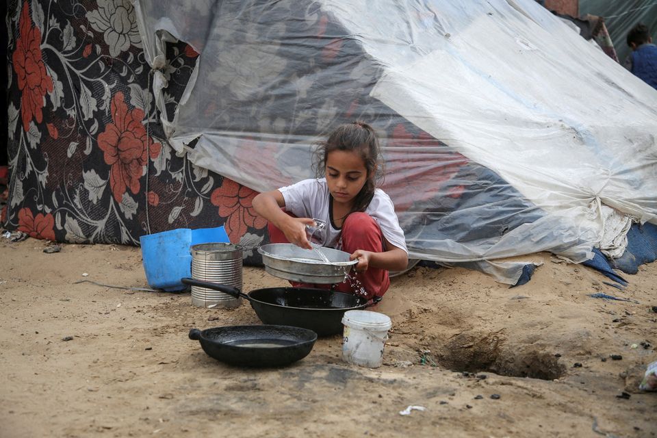 A girl pours water next to a tent, amid the ongoing conflict between Israel and Palestinians, in Rafah in the southern Gaza Strip. Reuters