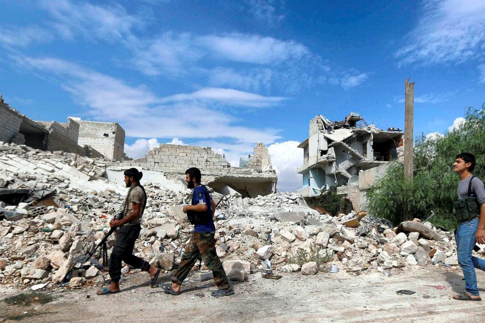 Rebel fighters carry their weapons as they walk towards their positions near Nairab military airport in Aleppo