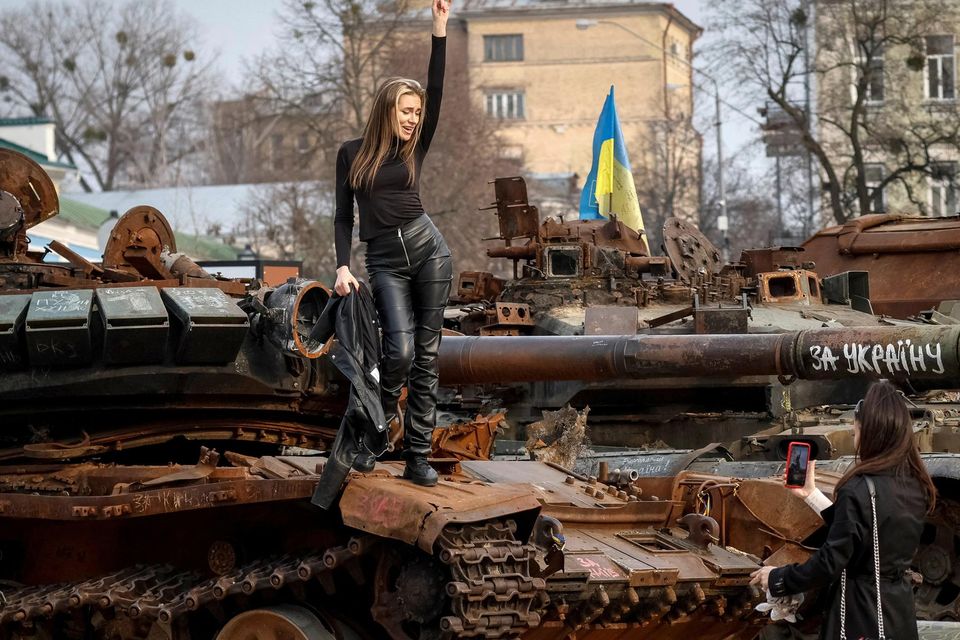 Women take a picture atop a destroyed Russian tank during an exhibition displaying destroyed Russian military vehicles in Kyiv. Photo: Gleb Garanich