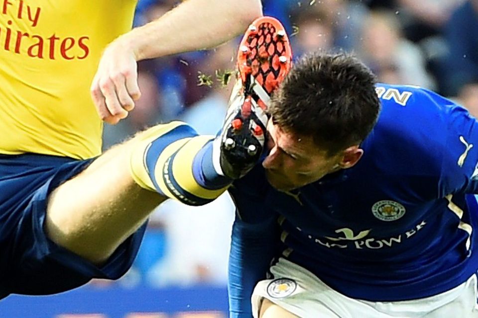 Arsenal's Per Mertesacker (L) catches Leicester City's David Nugent in the face with his boot