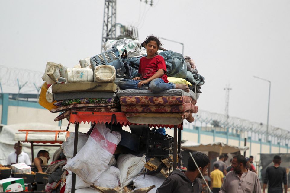 A girl watches as Palestinians travel on foot along with their belongings, fleeing Rafah due to an Israeli military operation, in Rafah, southern Gaza Strip, May 28, 2024. REUTERS/Hatem Khaled