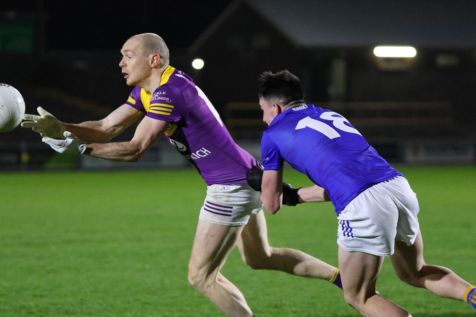 Kevin O'Grady delivers a pass as Cillian McDonald of Wicklow moves in to tackle.