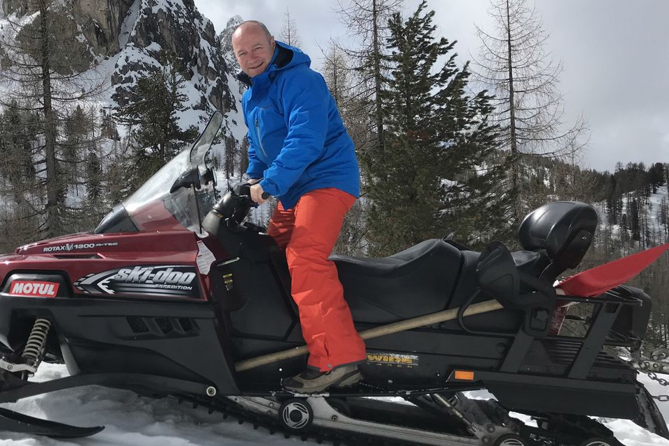 Communications expert Alan Shortt, who is also well known as a comedian, poses on a Cortina snowmobile, “downhill slopes can be an adrenaline rush”