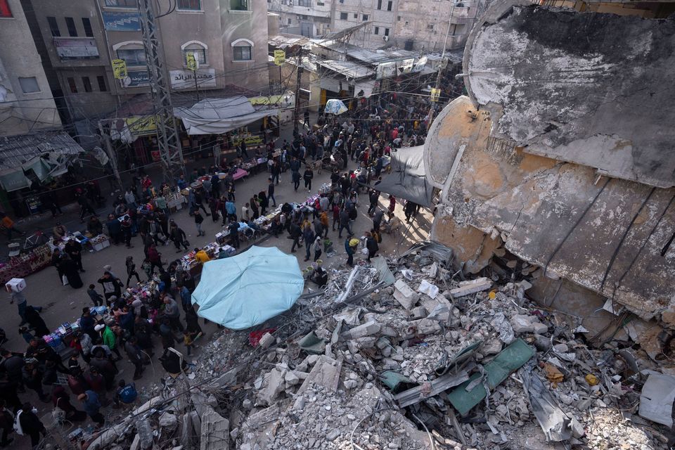 Palestinians shop at a local market next to a destroyed residential building by the Israeli airstrikes, during the Muslim holy month of Ramadan, in Rafah, Gaza Strip, Thursday, March 14, 2024. (AP Photo/Fatima Shbair)