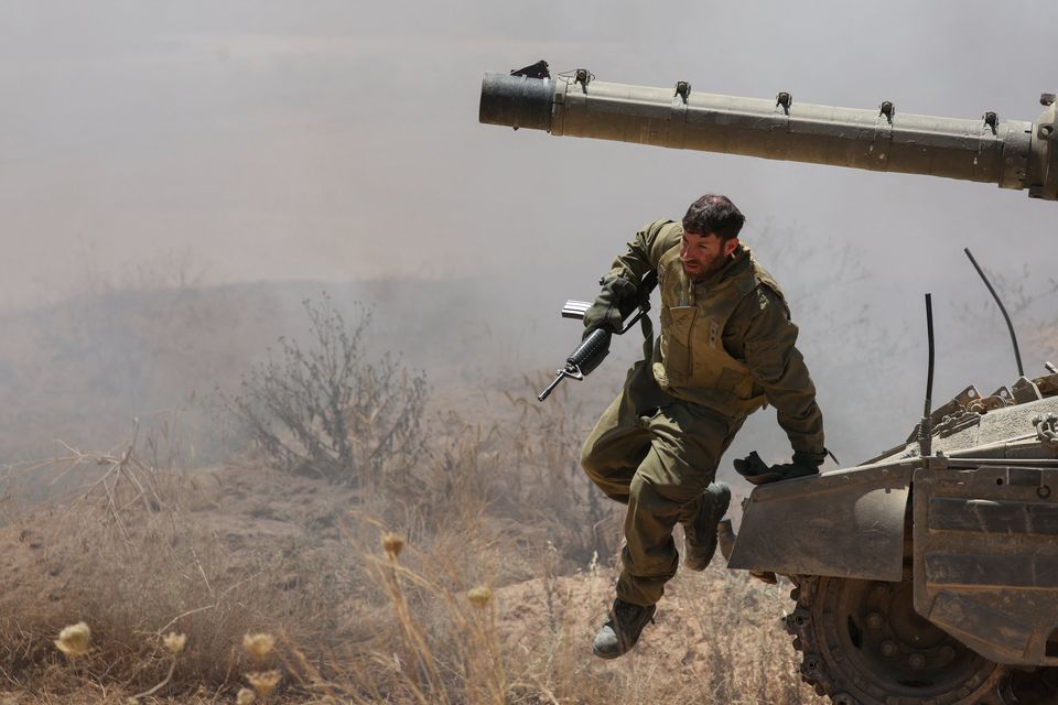 An Israeli soldier jumps off a tank, near the Israel-Gaza border, in Israel on Thursday. Shannon Stapleton/Reuters