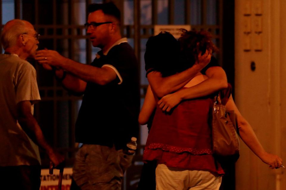 People comfort each other in the aftermath of the truck rampage in Nice. Below: Passers-by walk with their hands over their heads as soldiers stand guard after Nice went into lockdown. Photo: AFP/Getty
