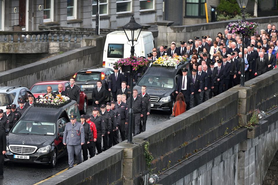 The funeral cortege of Laurence and Martina Hayes is accompanied by guards of honour from the Order of Malta and work colleagues of Mr Hayes