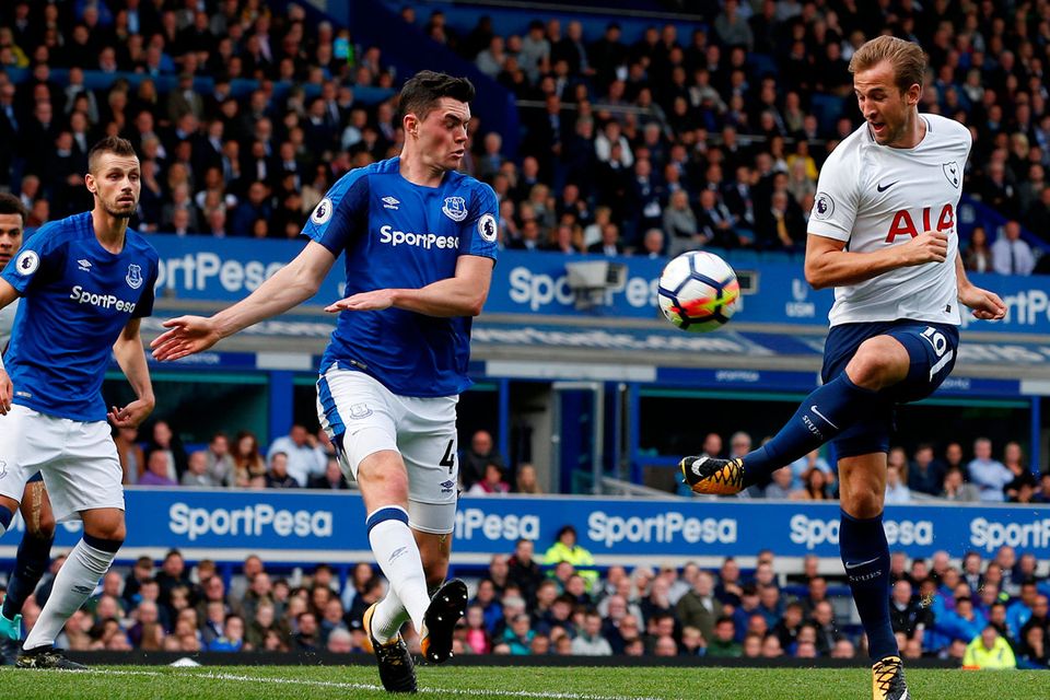 Harry Kane gets in his shot despite the efforts of Michael Keane. Photo: Andrew Yates/Reuters